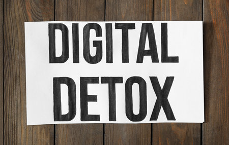 White paper sheet with words DIGITAL DETOX on wooden background, top viewの写真素材