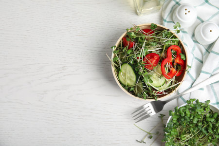 Salad with fresh organic microgreens in bowl on white table, flat lay. Space for textの写真素材