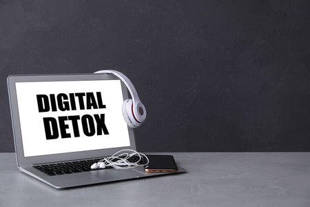 Headphones, earphones and laptop with words DIGITAL DETOX on light grey table. Space for textの写真素材