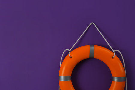 Orange lifebuoy and space for text on violet background. Rescue equipmentの写真素材