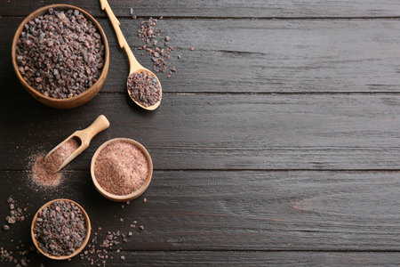 Black salt on wooden table, flat lay. Space for textの写真素材