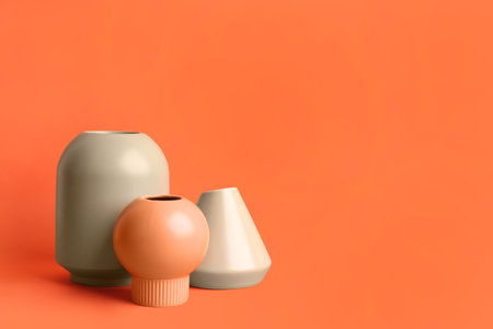 Stylish empty ceramic vases on orange background, space for textの写真素材