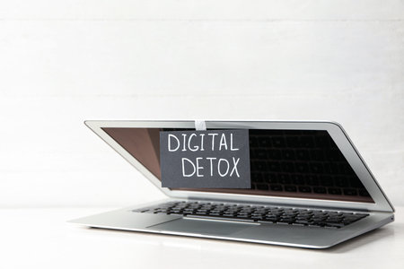 Laptop and paper with words DIGITAL DETOX on white wooden tableの写真素材