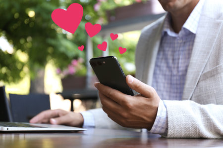 Man dating site visiting via smartphone in outdoor cafe, closeupの写真素材