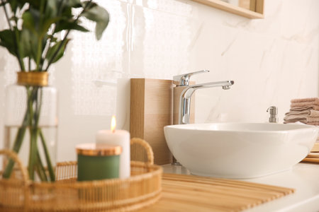 Vase with beautiful branches, candles and fresh towels near vessel sink in bathroom. interior designの写真素材