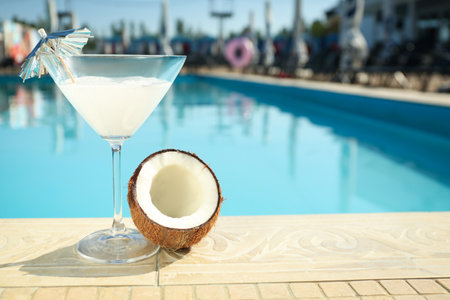 Tasty refreshing cocktail and coconut on edge of swimming pool. party items