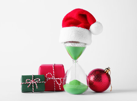 Hourglass with Santa hat and festive decor on white background. christmas count down