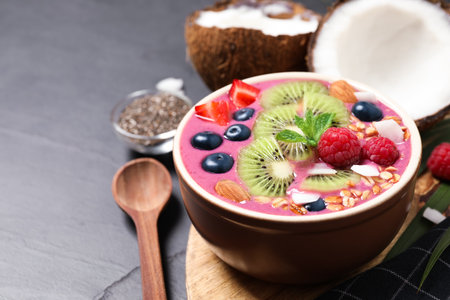 Delicious acai smoothie with granola and fruits served on black table, closeup. Space for textの写真素材