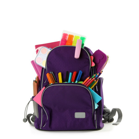 Purple backpack with different school stationery on white background
