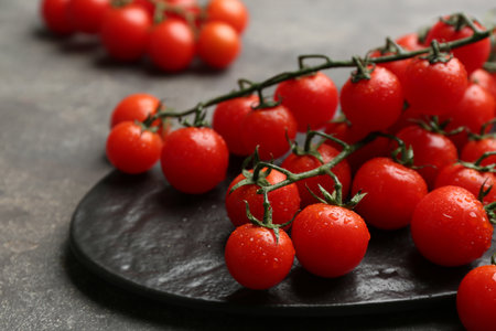 Fresh ripe cherry tomatoes with water drops on gray table, closeupの写真素材