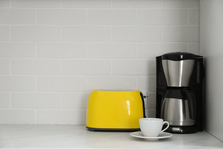 Modern yellow toaster and coffeemaker on countertop in kitchen. Space for textの写真素材