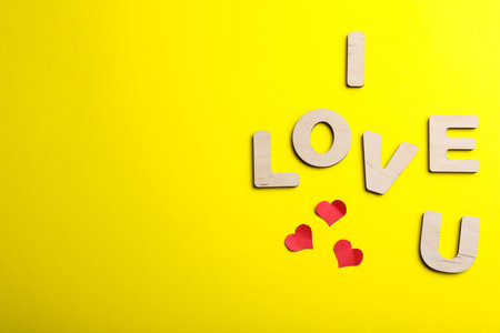 Phrase I Love You made of wooden letters on yellow background, flat lay. Space for textの写真素材