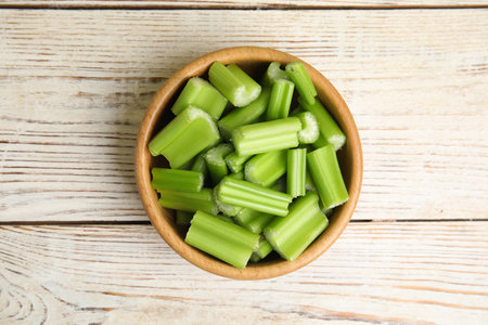 Cut celery in bowl on white wooden table, top viewの写真素材
