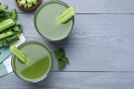 Celery juice and fresh ingredients on gray wooden table, flat lay. Space for textの写真素材