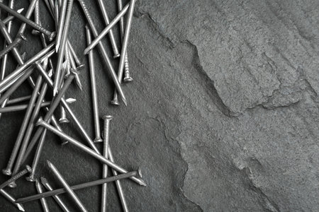 Many metal nails on gray background, flat lay. Space for text