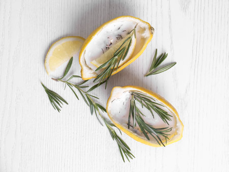 Lemon candles and fresh rosemary on white wooden table, flat lay. natural homemade repellentの写真素材