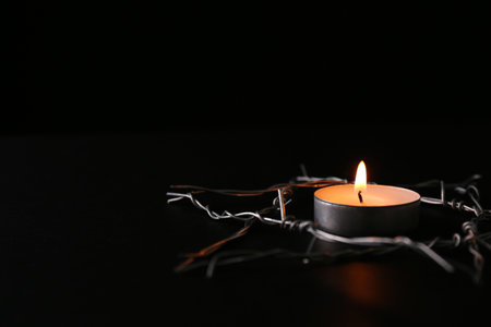 Burning candle and star of David made with barbed wire on black background, space for text.の写真素材