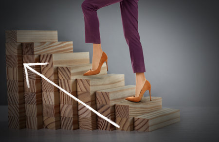 Businesswoman walking up stairs against grey background, closeup. Career ladder conceptの写真素材