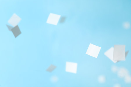 White confetti falling down on light blue backgroundの写真素材