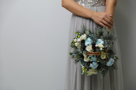 Bride holding beautiful winter wedding bouquet on light gray background, closeup. Space for textの写真素材