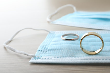 Protective masks and wedding rings on wooden table.の写真素材