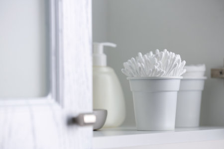 Container with cotton buds on shelf indoors
