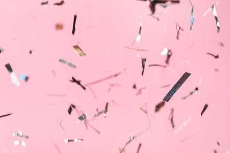 Shiny silver confetti falling down on pink backgroundの写真素材