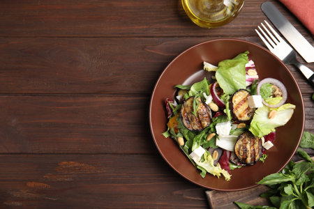 Delicious salad with roasted eggplant, feta cheese and arugula served on wooden table, flat lay. Space for textの写真素材