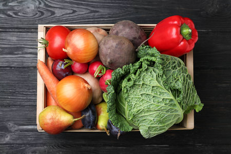 Crate full of different vegetables and fruits on black wooden table, top view. Harvesting timeの写真素材