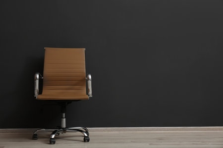 Comfortable office chair near black wall indoors. Space for textの写真素材