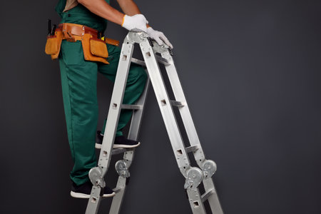 Professional constructor climbing ladder on black background, closeupの写真素材