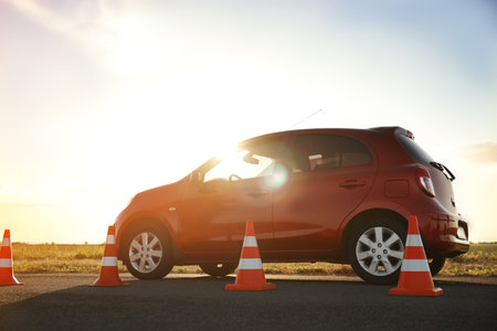 Traffic cones near red car outdoors. Driving school examの写真素材
