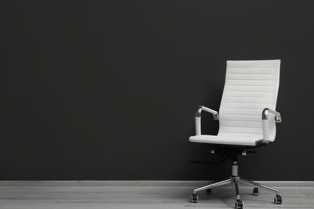 Comfortable office chair near black wall indoors. Space for textの写真素材