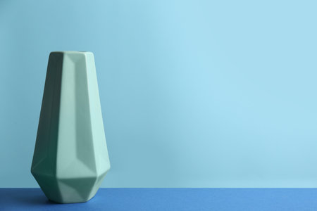 Stylish green ceramic vase on table against light blue background, space for textの写真素材