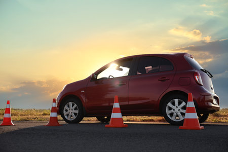 Traffic cones near red car outdoors. Driving school examの写真素材
