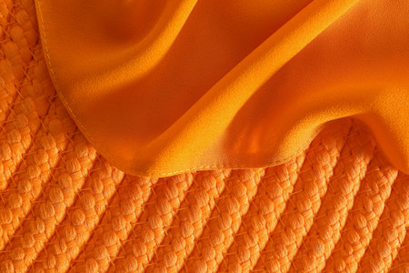 Orange fabric on wicker mat, top viewの写真素材