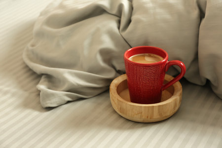 Cup of aromatic coffee on bed with soft blanketの写真素材