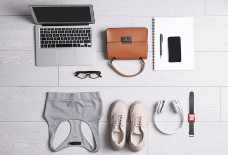 Flat lay composition with business supplies and sport equipment on white wooden floor. Concept of balance between work and lifeの写真素材