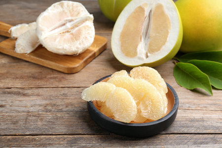 Bowl with peeled pomelo slices on wooden table, closeupの写真素材