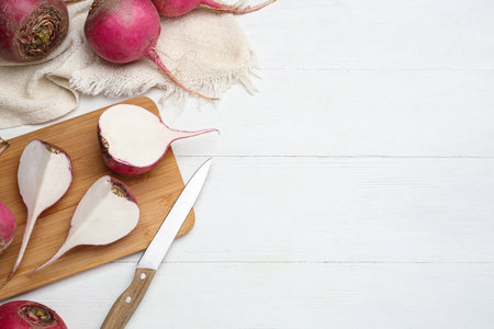 Cut and whole red turnips on white wooden table, flat lay. Space for textの写真素材