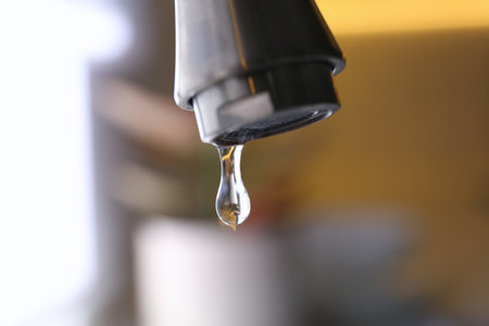 Water drop falling down from tap on blurred background, closeupの写真素材