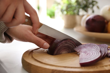 Woman cutting red onion into slices at countertop in kitchen, closeupの写真素材