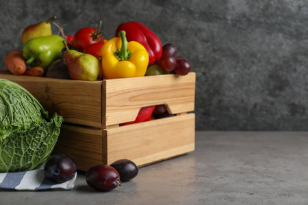 Wooden crate full of different vegetables and fruits on grey table, space for text. Harvesting timeの写真素材
