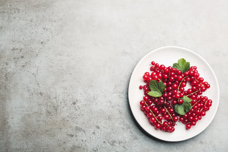 Delicious red currants and leaves on light grey table, top view. Space for textの写真素材