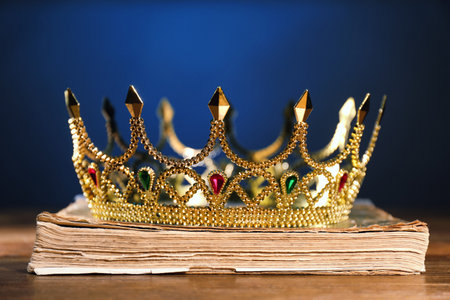 Beautiful golden crown on old book against dark blue background. Fantasy itemの写真素材