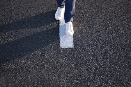 Man walking along white line on road, closeup with space for text. Way concept