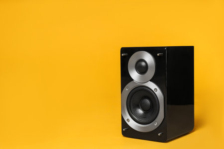 Modern powerful audio speaker on yellow background, space for textの写真素材