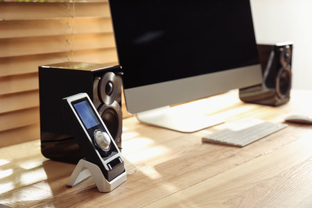 Modern computer with audio speakers and remote on table indoorsの写真素材