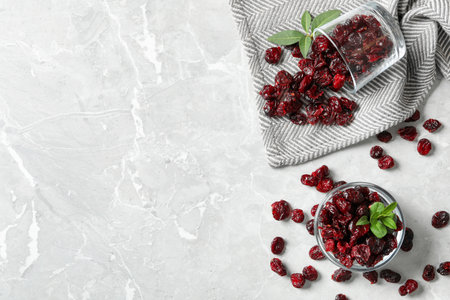 Flat lay composition with tasty dried cranberries and leaves on gray table. Space for textの写真素材