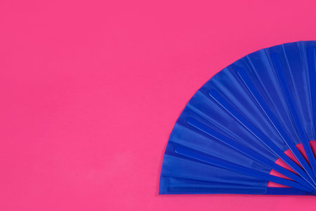 Blue hand fan on pink background, top view. Space for textの写真素材